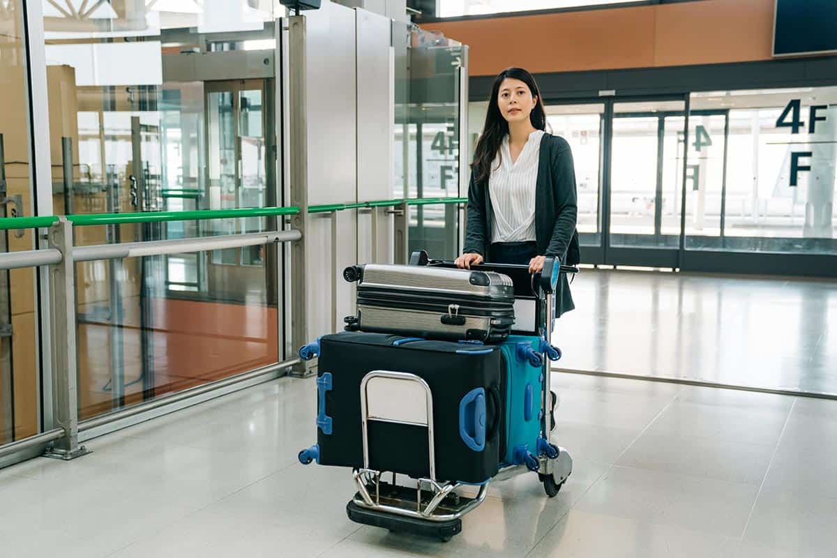 Woman walking in kansai international airport pushing luggage cart