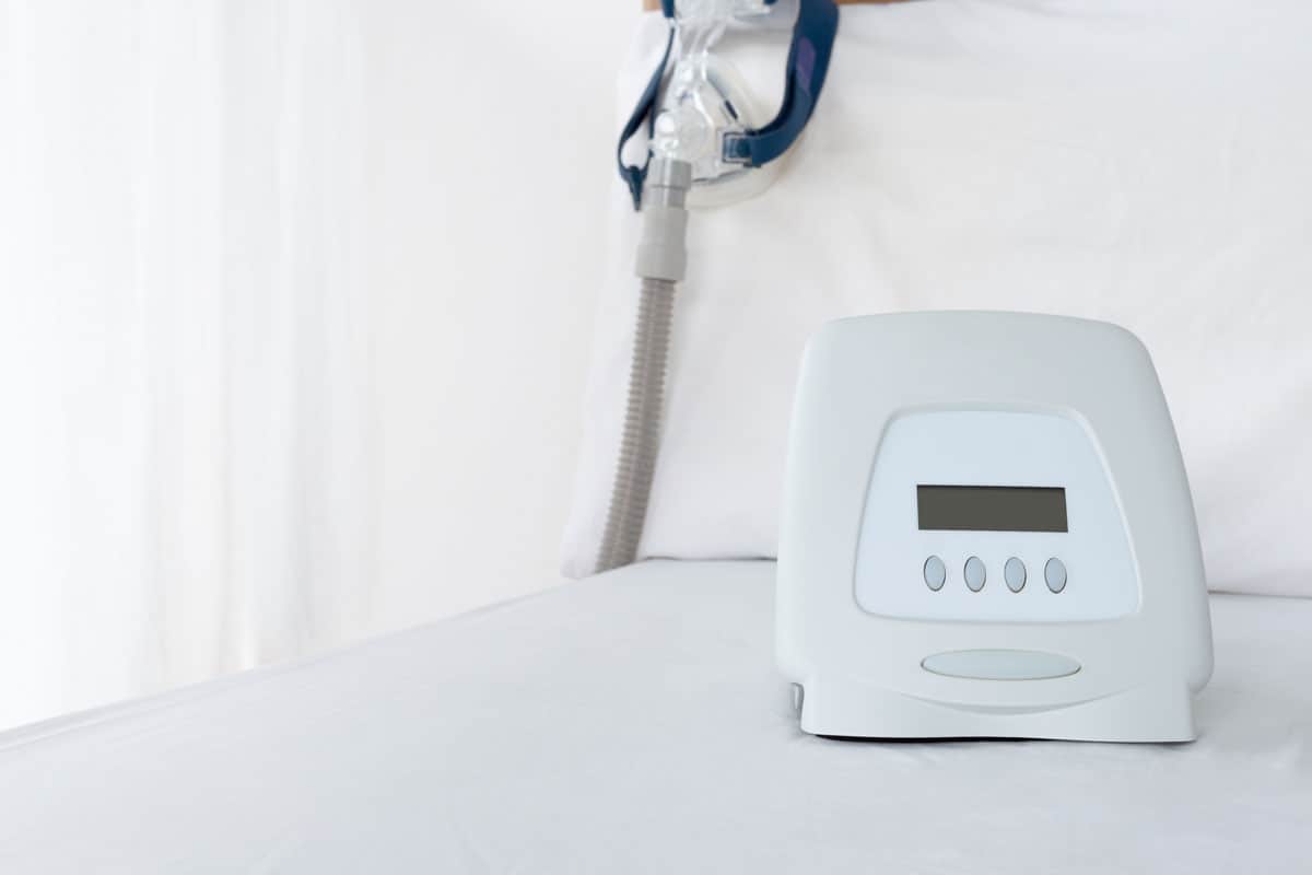bright photo of a cpap machine on a white room, white wall, white bed sheet