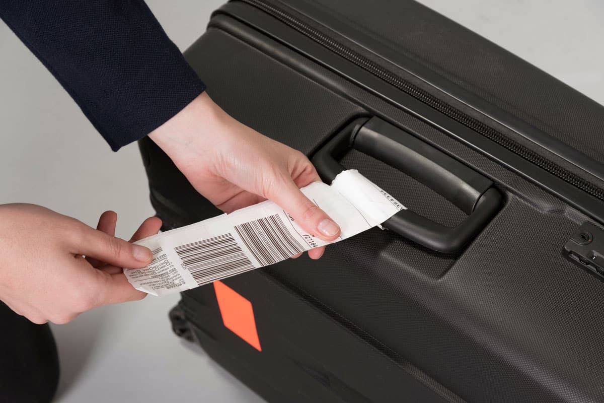 close up photo of a female hands, staff of the airport, applying tag on a luggage