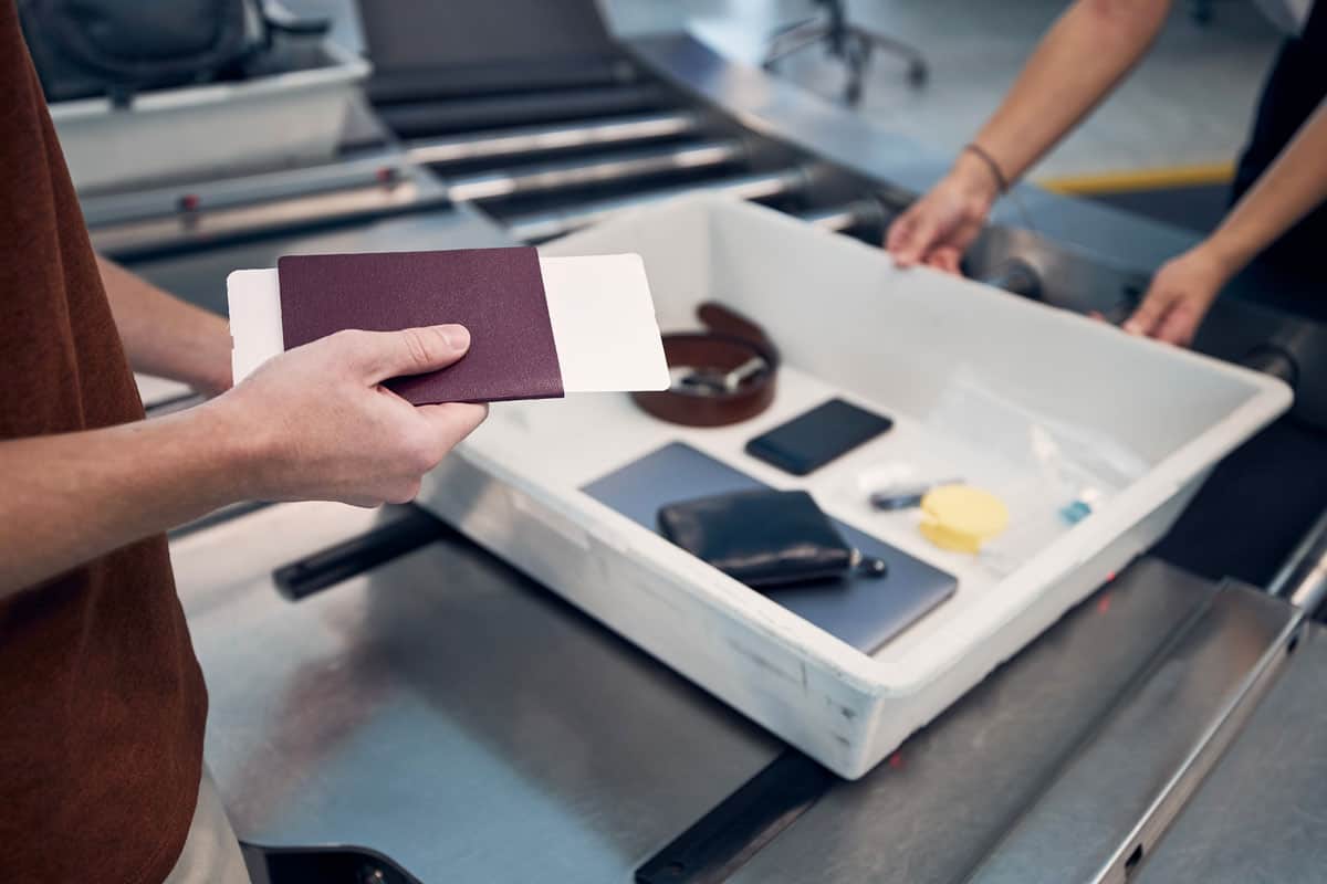 Holding passport. Personal items on tray. Airport scan. Airport security