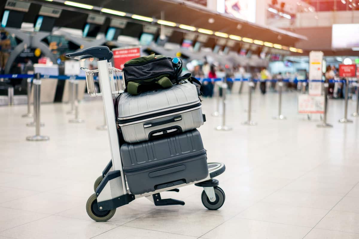 passenger luggage on the luggage cart, grey luggage on the bottom, silver luggage on the middle and small black bag on the top