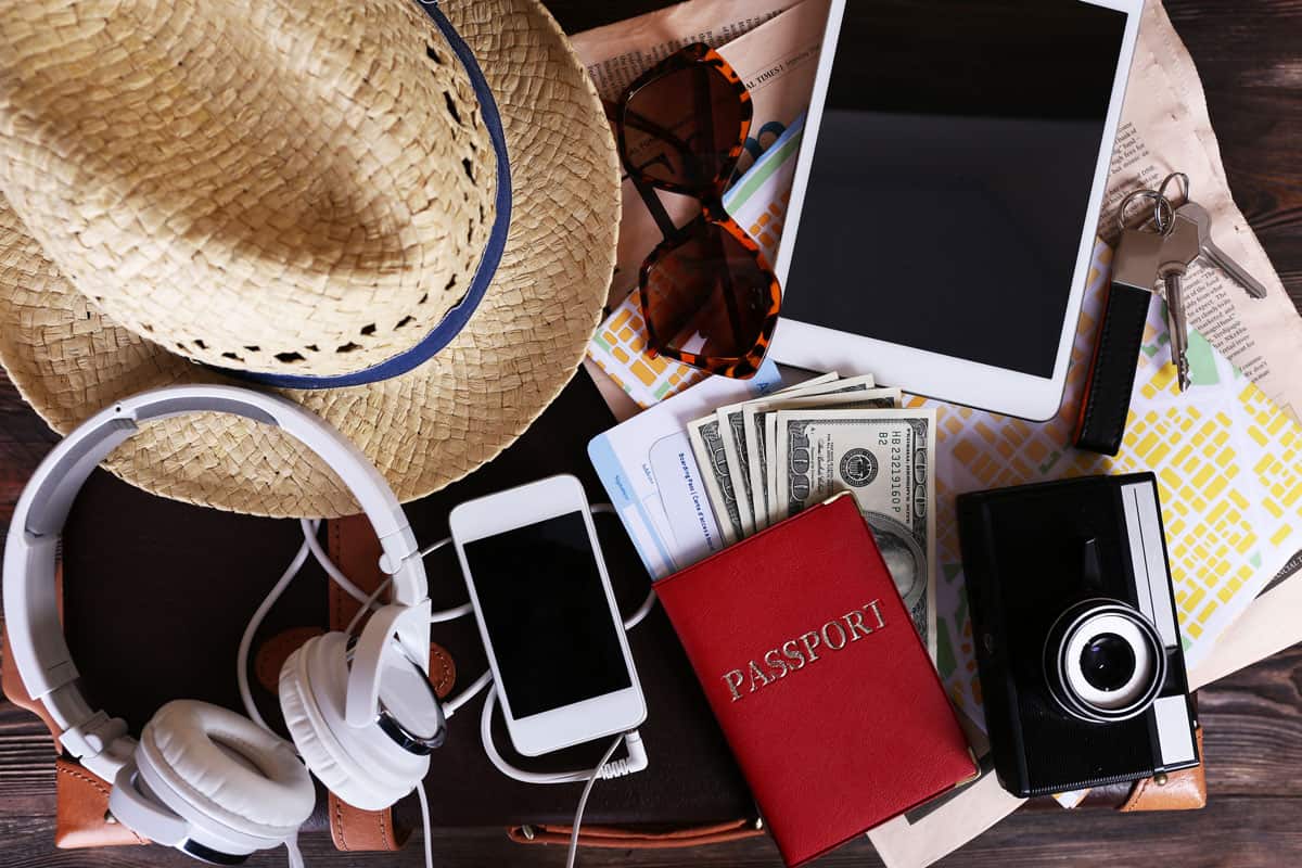 Photo showing personal stuffs like hat, sunglasses, headphones, mobile phones, camera, tablet and passport
