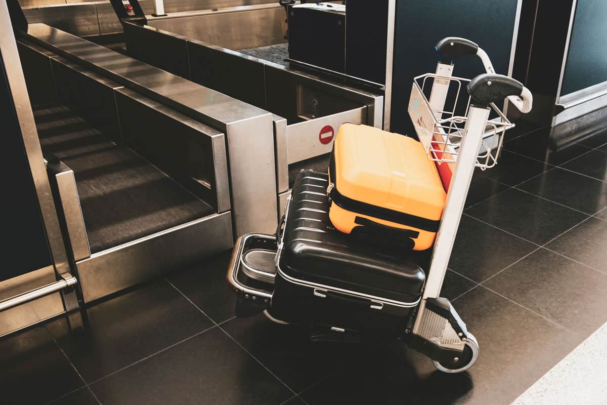 2 luggage on the luggage carrier or cart, big black luggage, small yellow luggage on top of black luggage