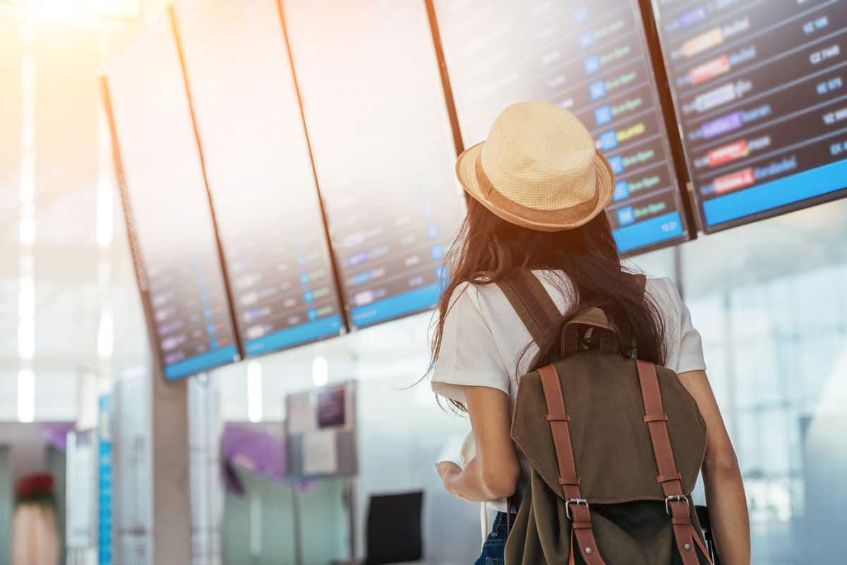Asian teenage girl is using a smartphone to check flight at the international airport to travel on weekends