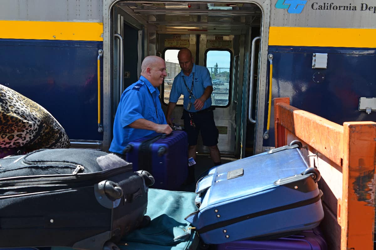 Baggage handlers load passengers' luggage aboard an amtrak California train
