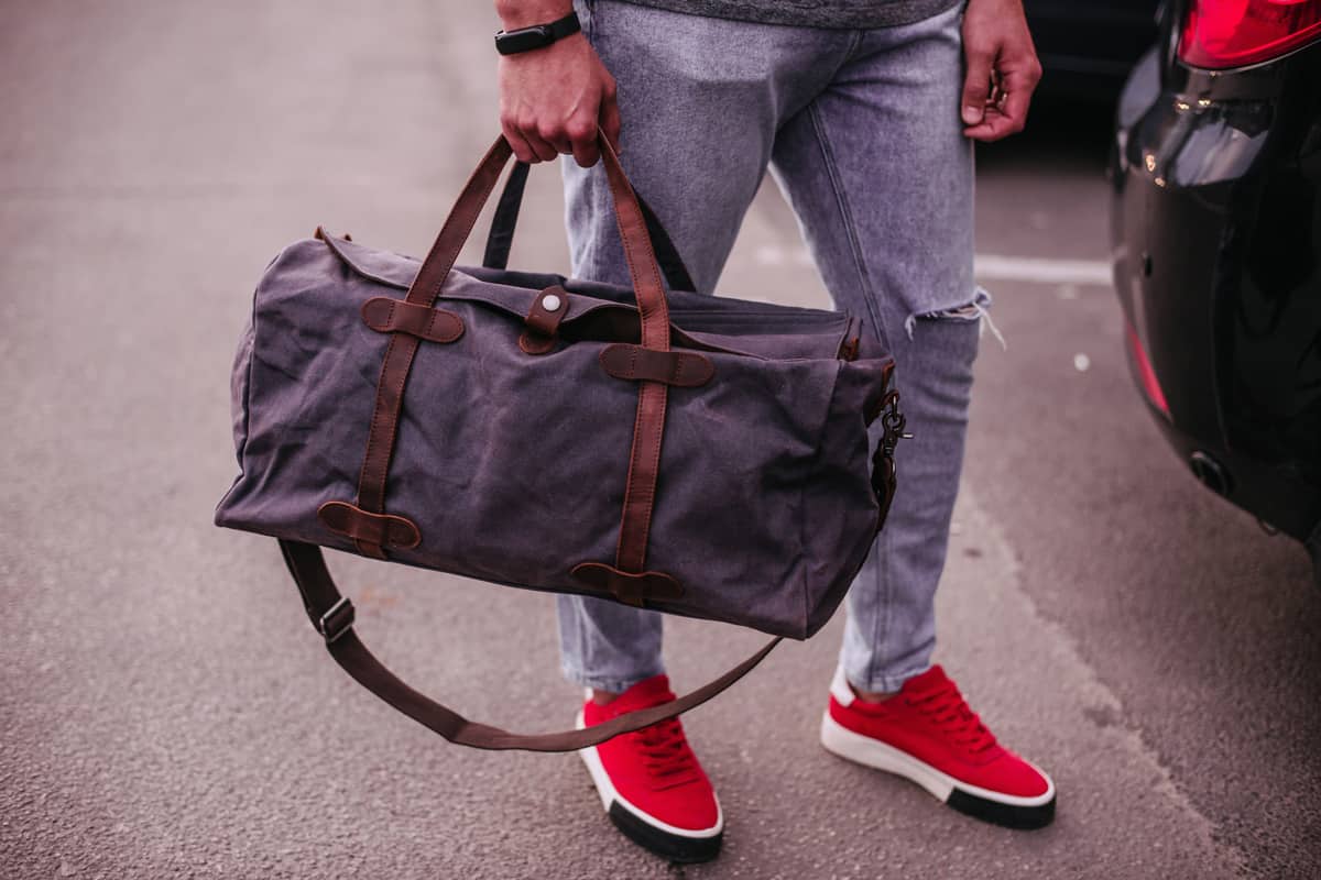 Cropped photo of a well-dressed man with a duffel bag.