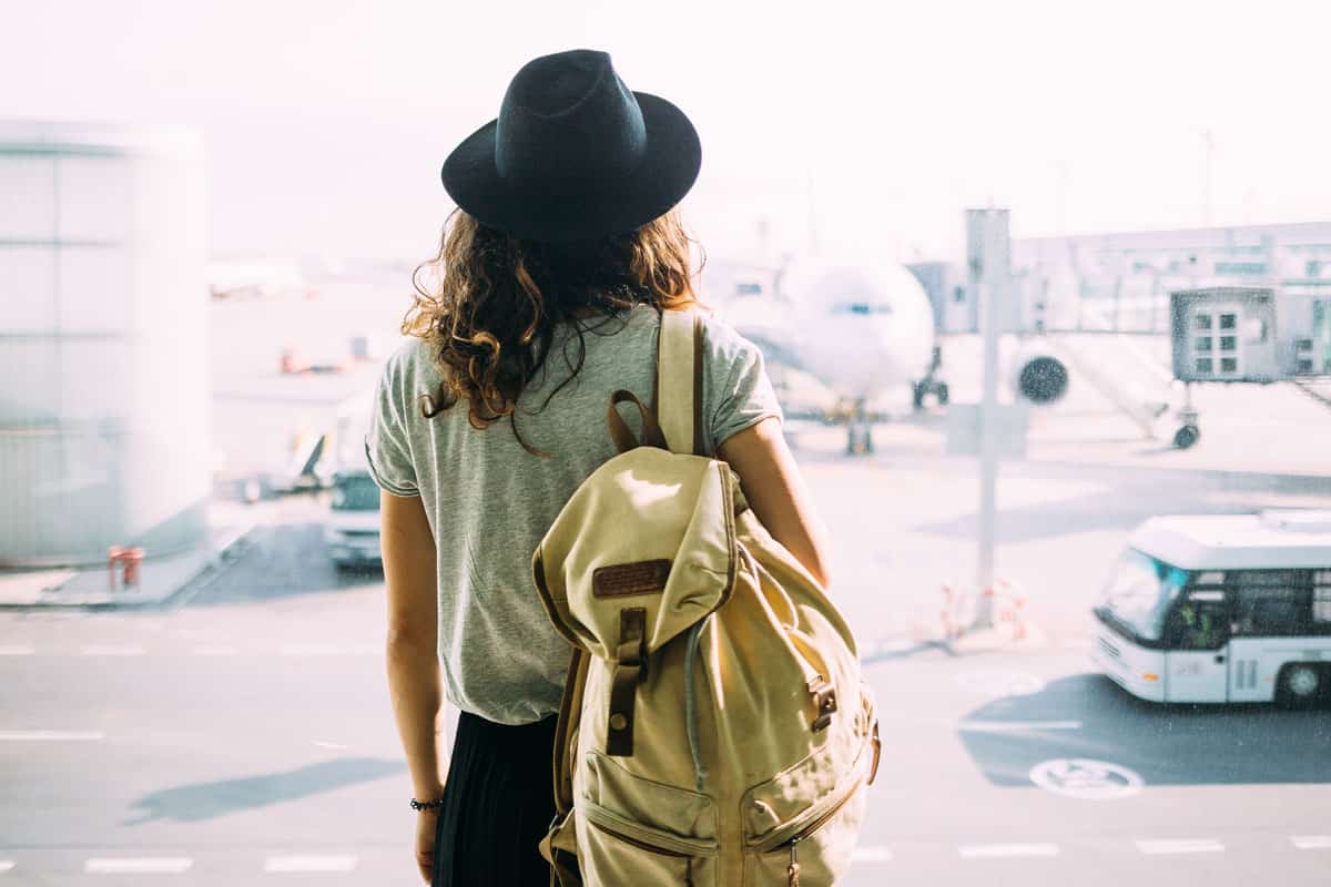 Girl in hat with backpack traveling in the airport