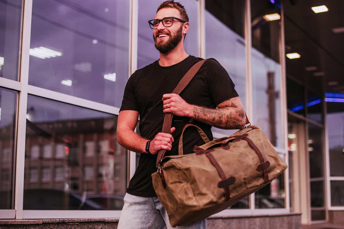 Man Casual Fashion. Man walking street with duffel canvas bag.