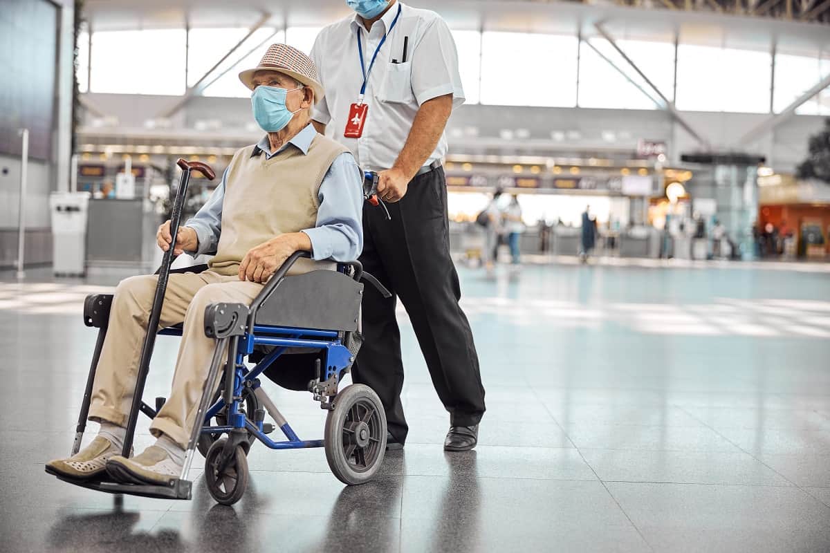 When Can Passengers with Disabilities and Parents of Young Children Board Serious aged Caucasian male tourist in a disposable protective mask sitting in a transport chair