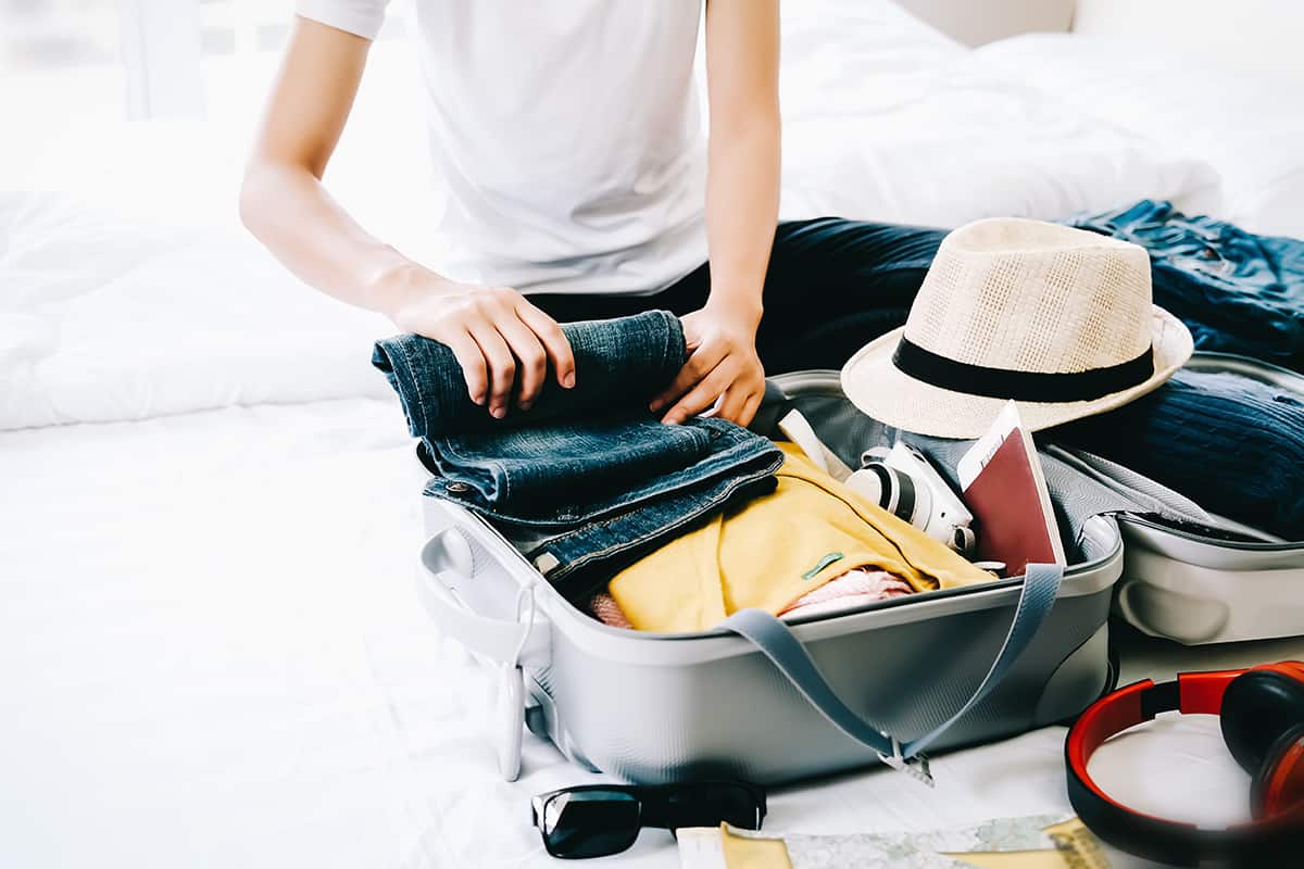 Woman packing travel bag for summer vacation