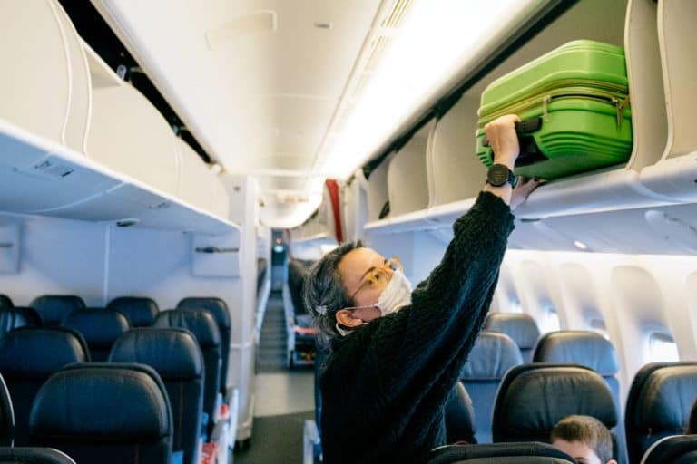 A woman storing carry on luggage on airplane overhead bin, Can I Bring A Digital Scale On An Airplane?