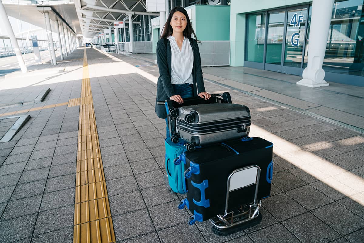 Woman traveler rolling luggage trolley
