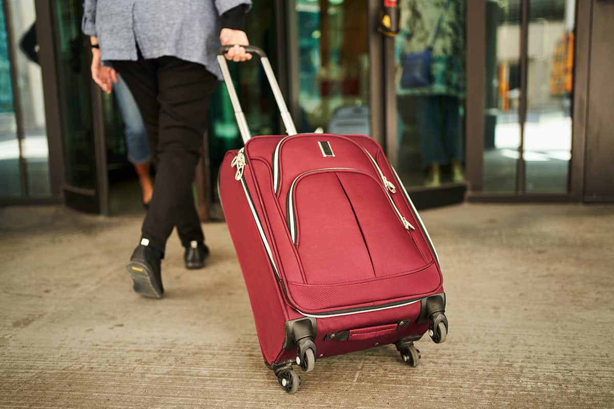 Woman walking into a hotel entrance pulling a suitcase