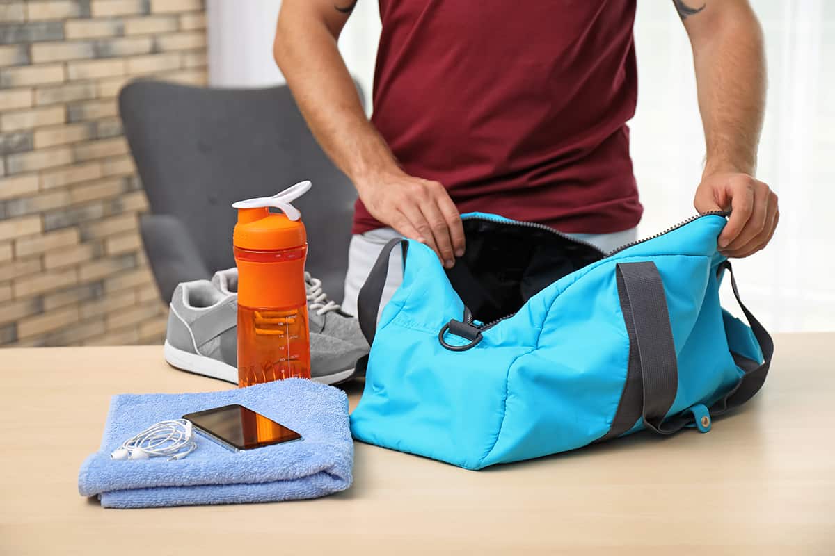 Young man packing sports bag on table