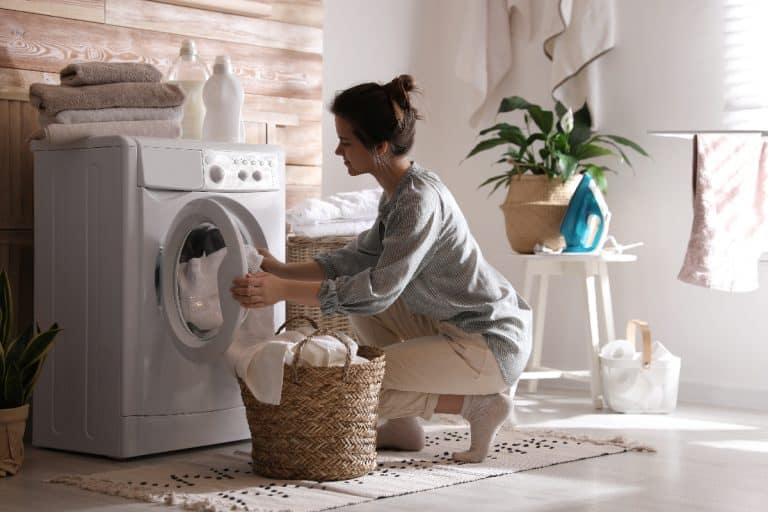 Young woman putting laundry on the washing machine, Can I Wash A Duffel Bag In The Washing Machine?