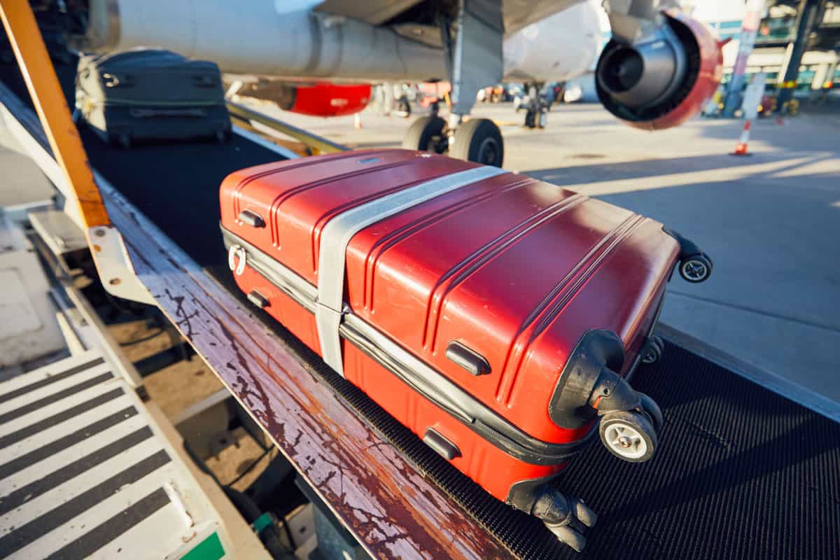 big red suitcase ready for loading to the aircraft along with other checked in suitcase