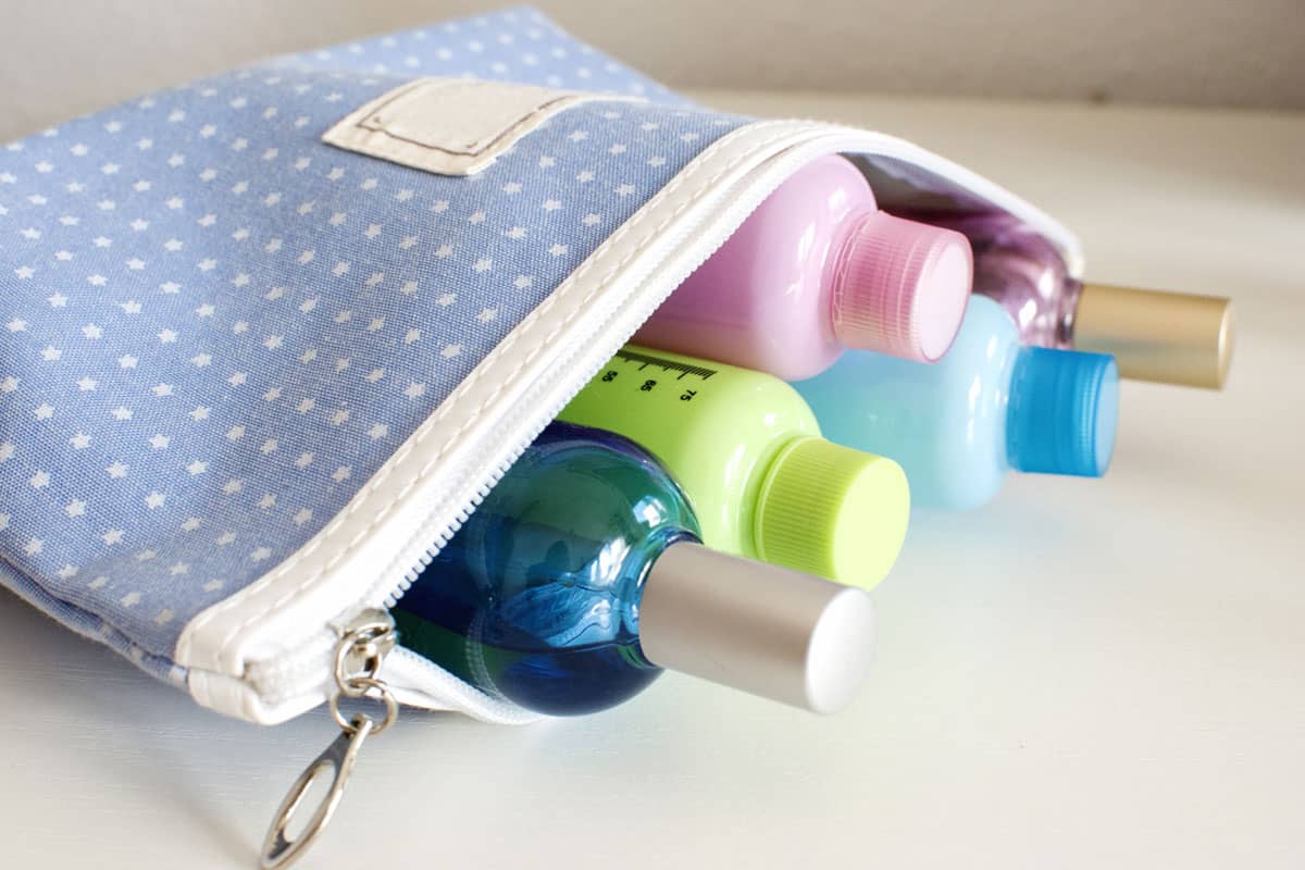 cute light blue toiletry bag, white background, liquid bottles, shampoo, conditioner, lotion