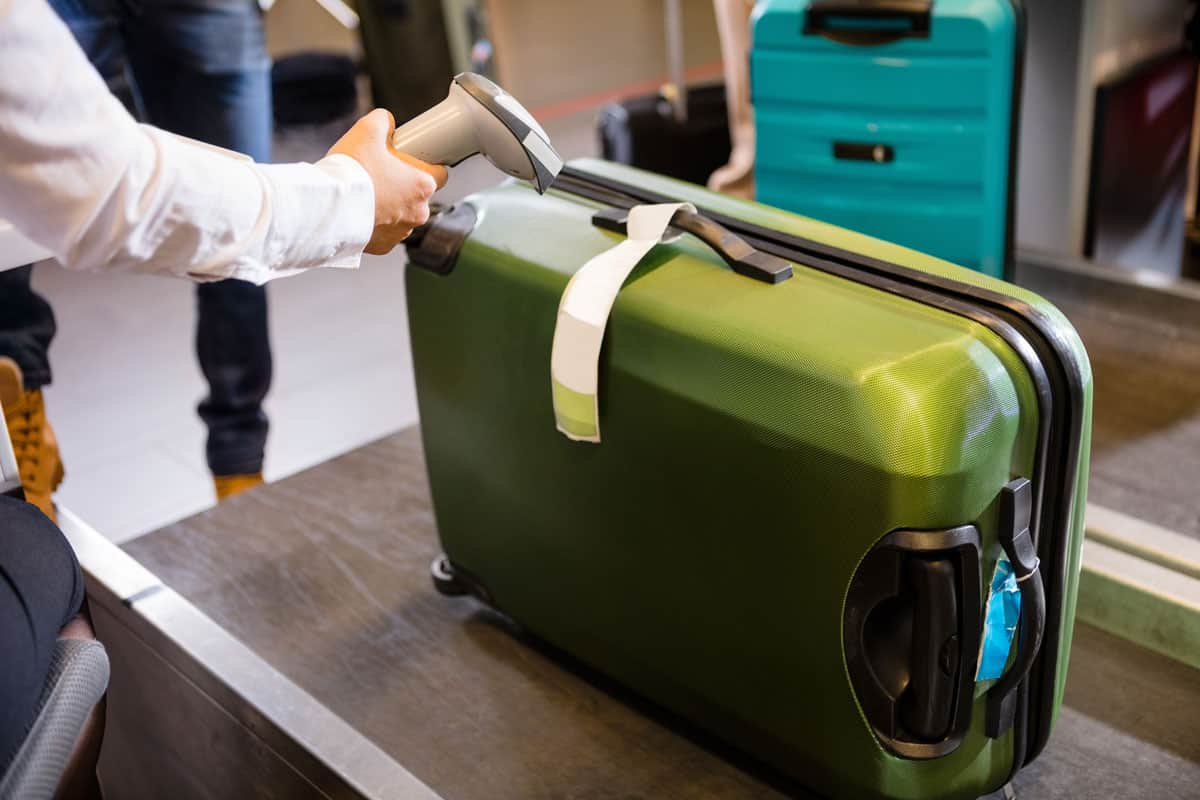 huge green luggage, scan by airport staff, ready to check in, airport terminal