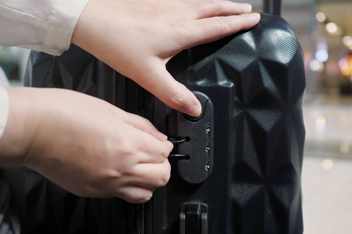 man unlocking the big black suitcase inside the airport