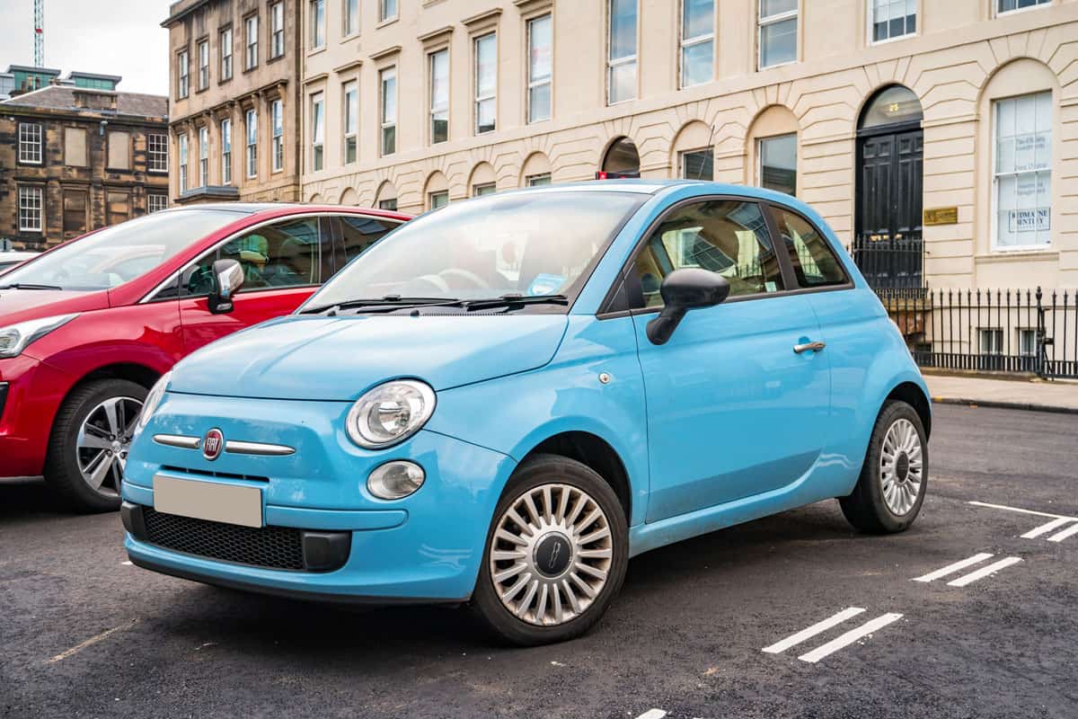 modern shiny sky blue fiat 500 car on the parking area outside of the building