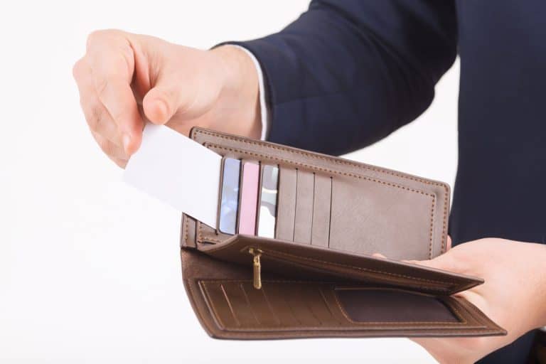 photo of a man holding a brown leather wallet showing cards and pictures inside, Are Wallet Size And Passport Size The Same?
