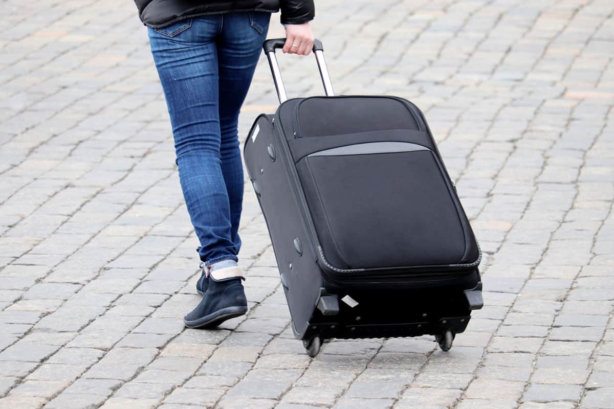 photo of a man pulling rolling luggage going to the airport terminal