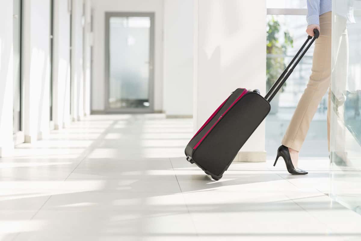 photo of a woman lady wearing high heels pulling black glider luggage