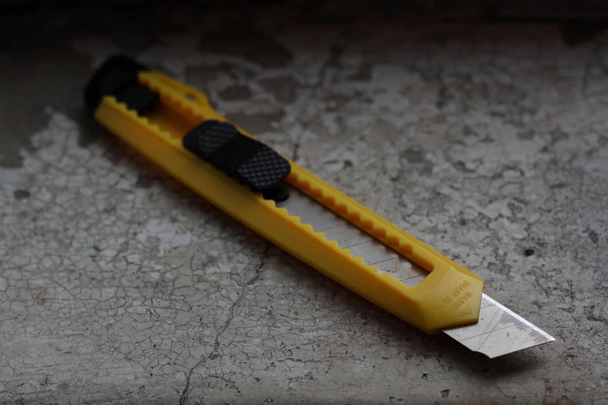 sharp yellow paper knife, close up picture, concrete floor