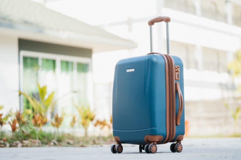 larger blue suitcase against the backdrop of the hotel lobby in the rays of sunlight. Vacation concept, summer travel. - Can You Replace Wheels On American Tourister Luggage?