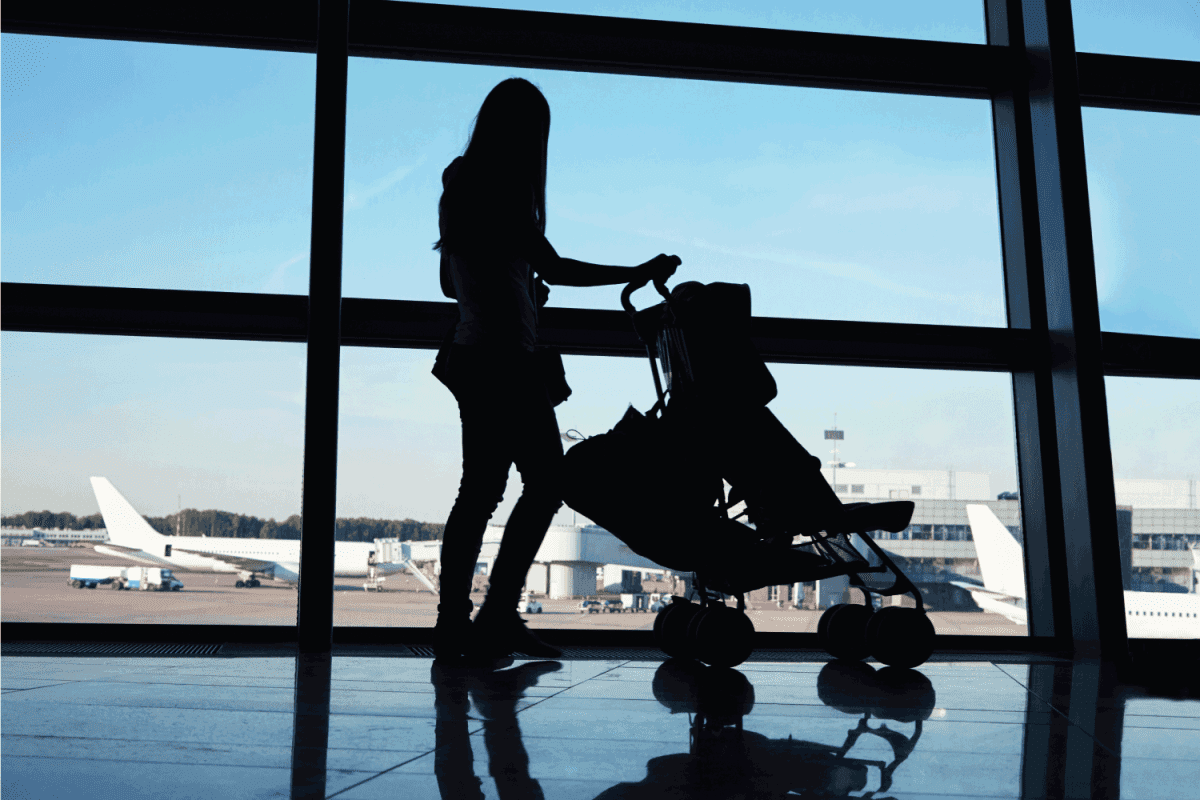 silhouette of a mother with baby in stroller in an airport waiting hall