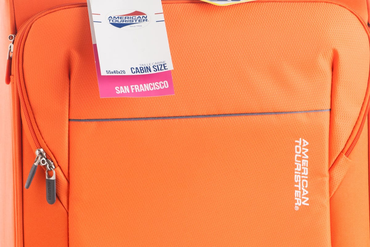 up close photo of an american tourister bag, orange colored suitcase