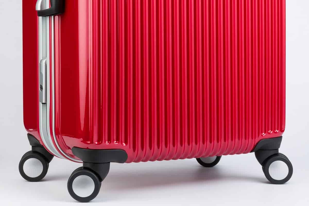 Ensure Wheels are Properly Aligned - Premium red travel suitcase with wheels, bottom side.