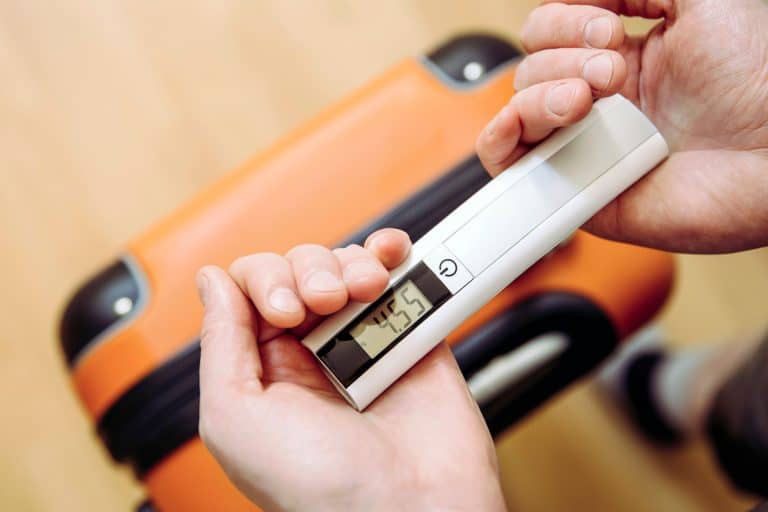 Man tourist using digital luggage scale at home to weighs luggage to avoid overweight baggage in airport concept. Reduce traveling stress. - Heys Luggage Scale Battery Change - How To