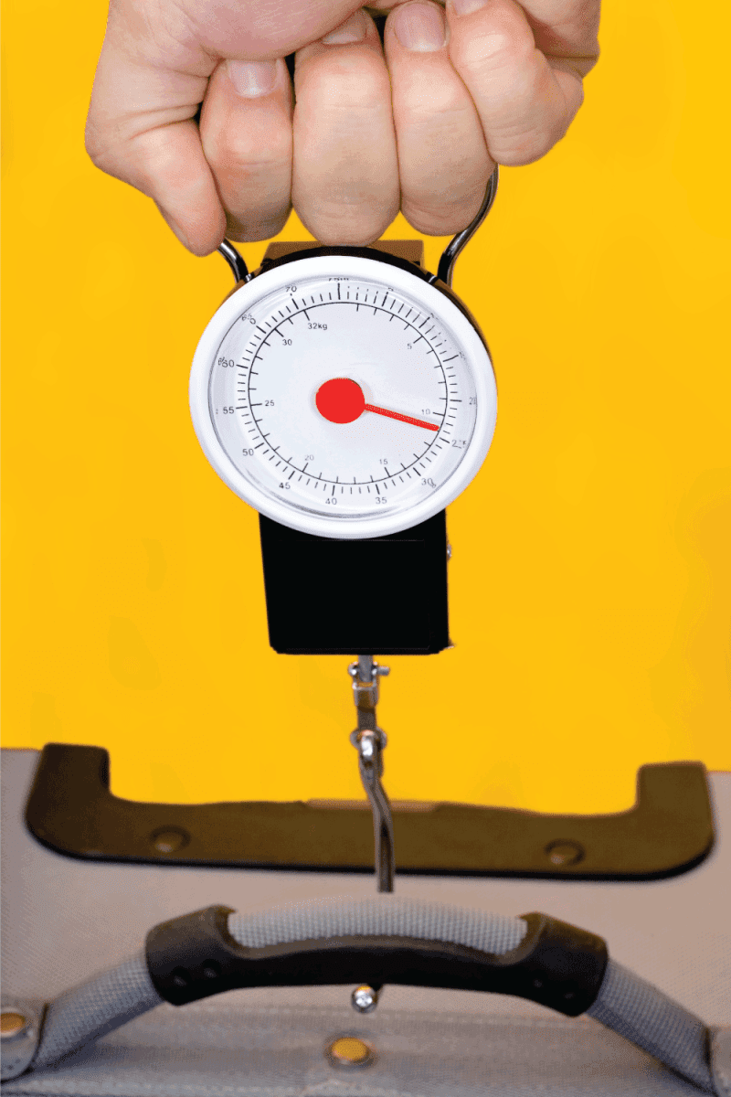 Measuring luggage with hand held scale. How heavy is your luggage