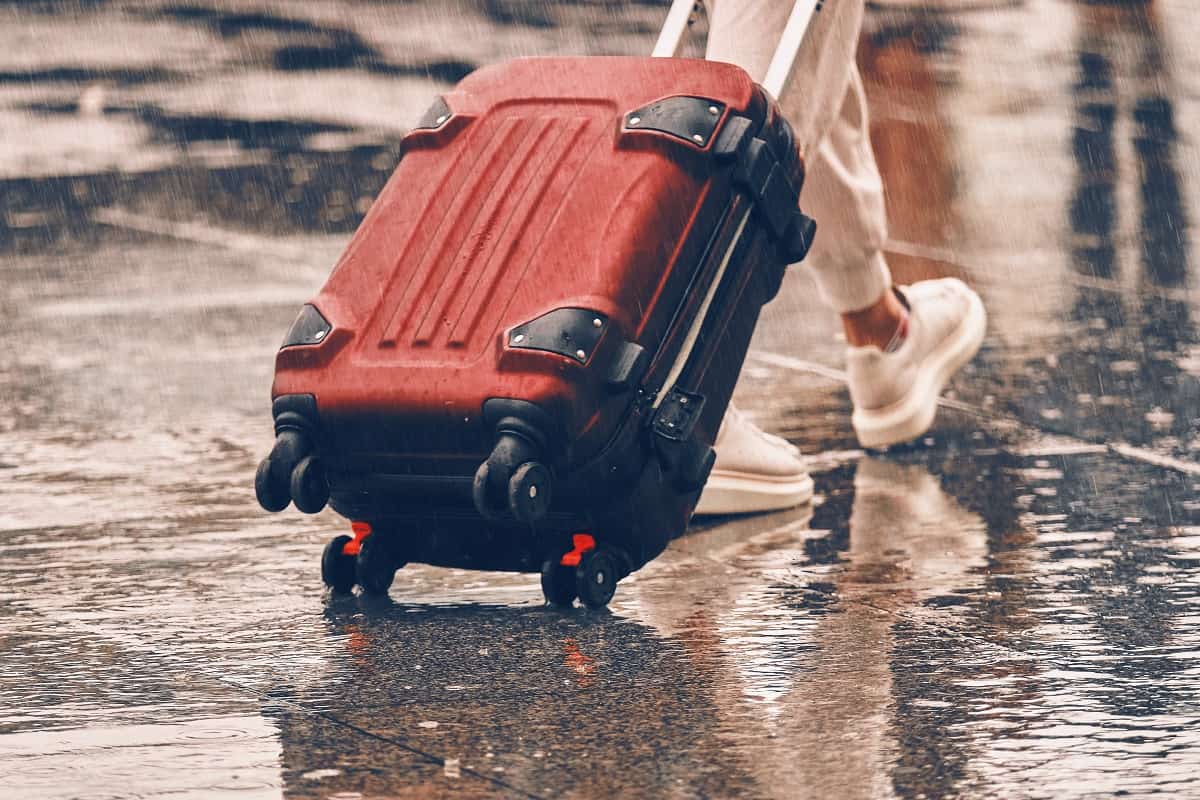 What's The Best Luggage To Use In Rainy Weather - Close-up suitcase in the hands of a lonely person