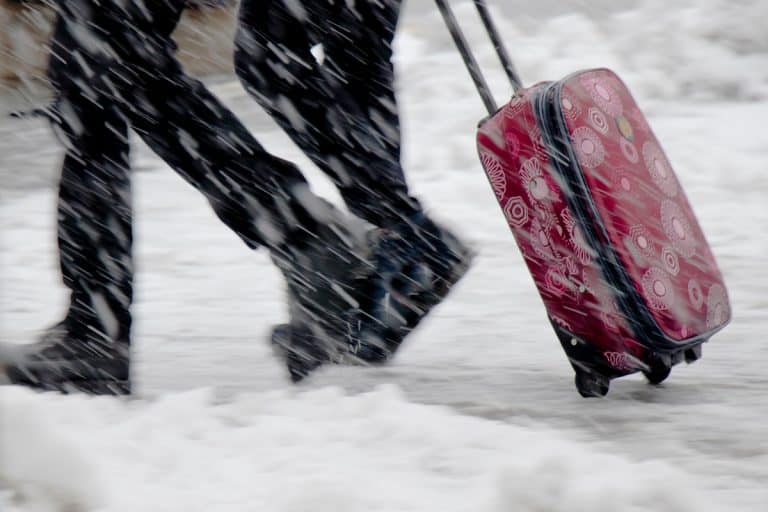 Winter travel; Blurry legs of two young people walking fast in heavy snowfall, How Can I Waterproof My Suitcase?