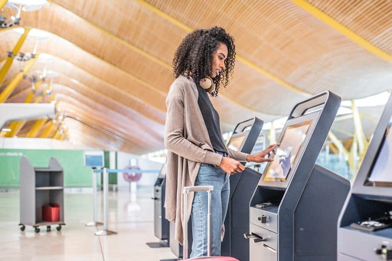 A woman using the check-in machine at the airport getting the boarding pass, How To Check-In For International Flight