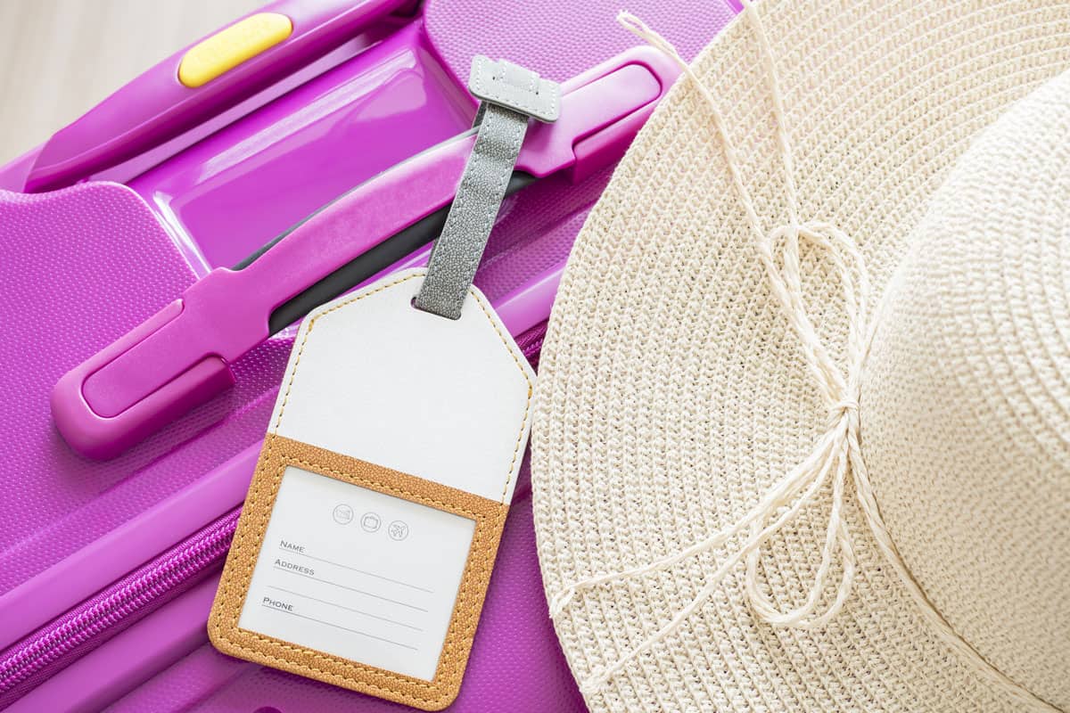 closeup-luggage-tag-white-hat-on-purple suitcase