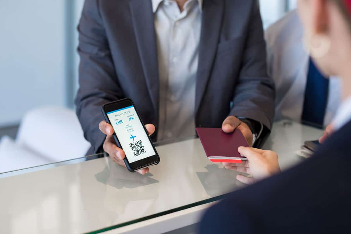 hand of man showing flight ticket to staff on phone
