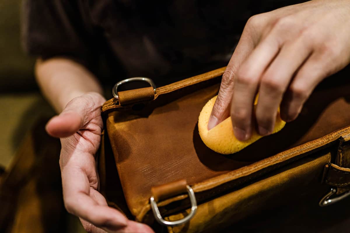photo of a man rubbing a sponge on the beis weekender bag gently
