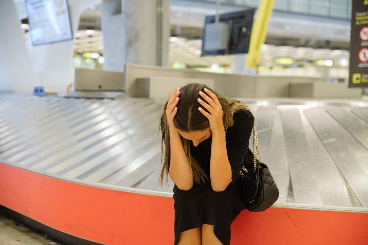 photo of a poor woman lost the luggage on the airport terminal very sad upset