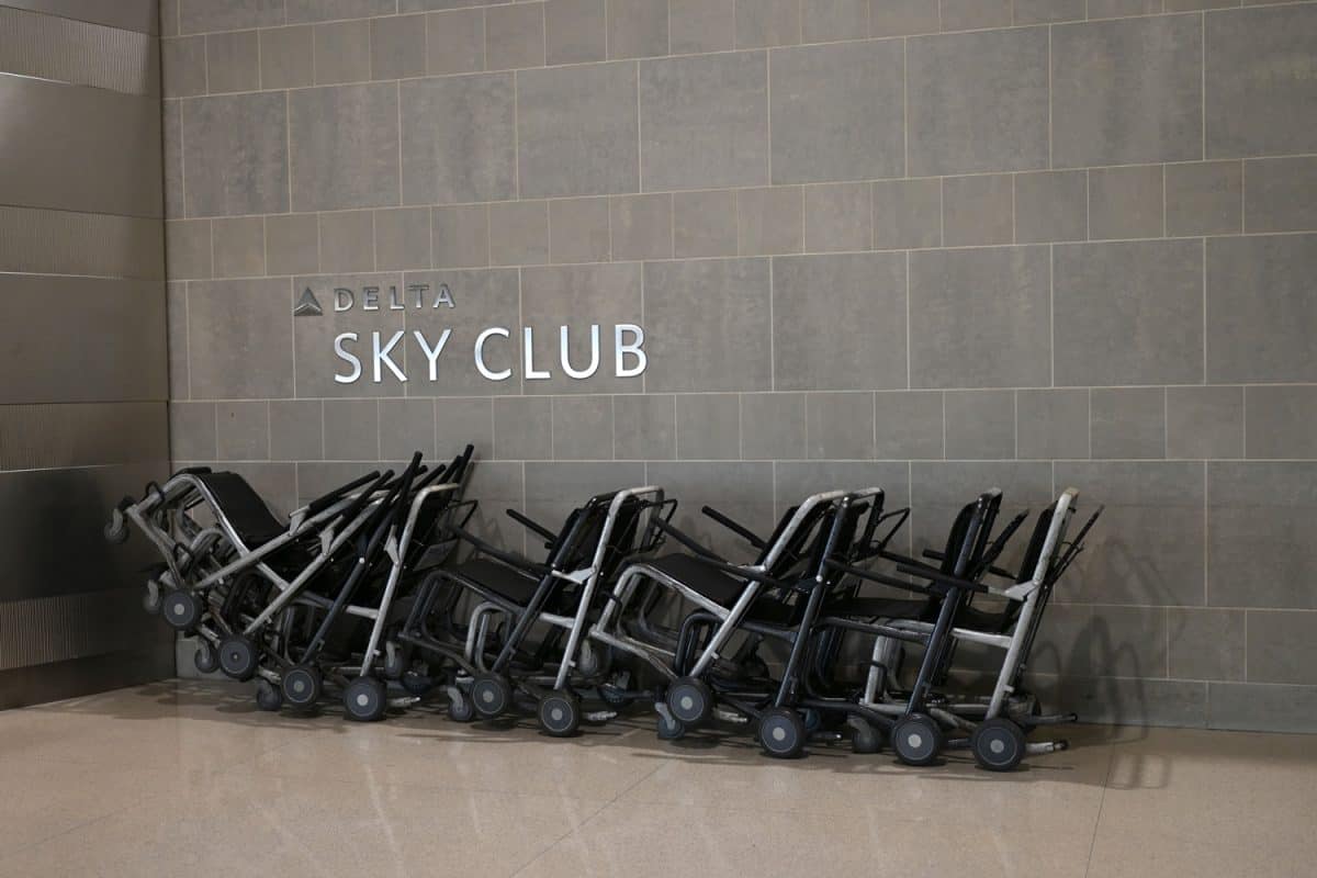 Lots of wheelchairs in front of a Delta Airlines Sky Club sign. Airport mobility assistance for old and disabled people