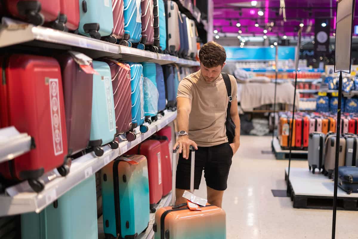 Man inspecting new suitcase in store.